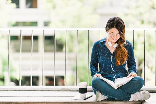 A young lady reading a book on the balcony